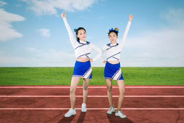 Two cheerleaders cheering at the football field