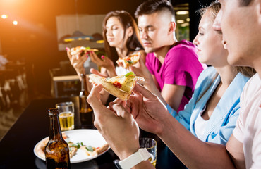 Cheerful friends in the pub. Drinking beer, eating pizza, talking, having fun.