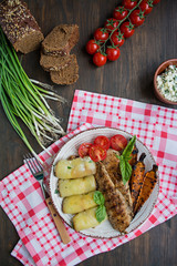 Grilled chicken fillet with baked vegetables, bell pepper rolls. Wooden background.