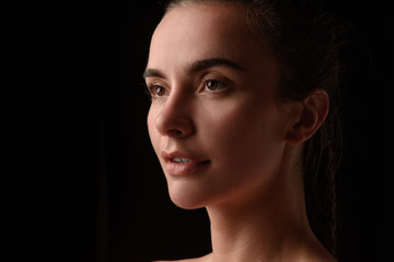 portrait of a young beautiful brunette girl on a black background