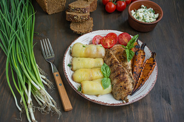 Grilled chicken fillet with baked vegetables, bell pepper rolls. Wooden background.