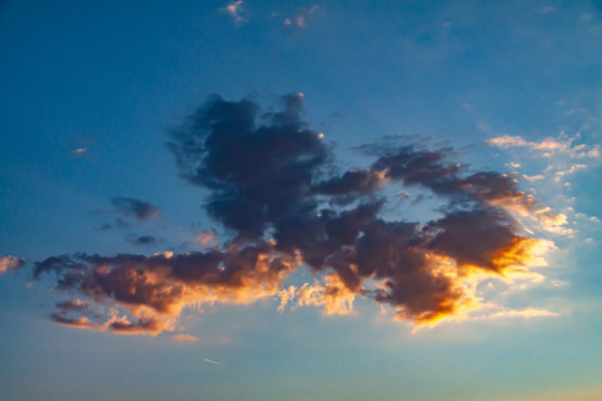 Cloud with golden and orange tones in a blue sky in a sunset, beautiful show of nature in Oensel south Limburg in the Netherlands