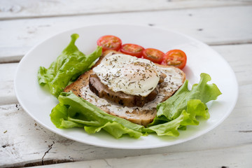 Fresh fried toast meat eggs tomatoes and herbs on white