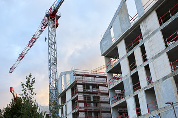 Construction of residential prefabricated houses with building crane. Bearing-wall multi story buildings under construction. Urban architecture, city landscape, real estate and municipal housing