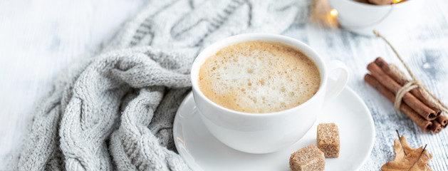Cup of coffee, brown sugar, knitted scarf, garland. Autumn mood. Cozy autumn composition. Hygge concept. Soft focus