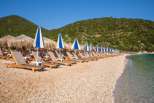 Summer sunny morning sunbeds and umbrellas of Antisamos beach on the Kefalonia island, Ionian sea, Greece.