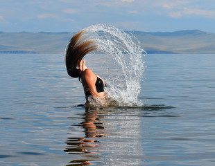 The girl waves her hair in the water.
