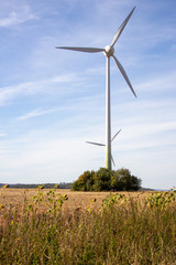 zwei hintereinander stehende Windkraftanlagen an einem sonnigen Herbsttag