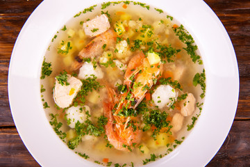 Shrimps soup and pieces of fish and fresh greens