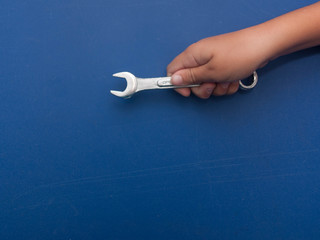 hand with spanner on a blue background