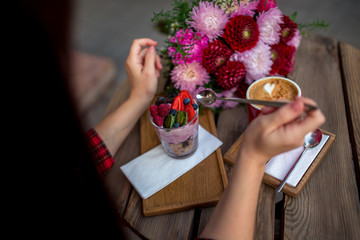 a girl sits in a cafe, eats dessert and on the table is a cup of aromatic coffee