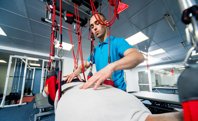 Physiotherapy. Suspension training therapy. Young man doing fitness traction therapy with...