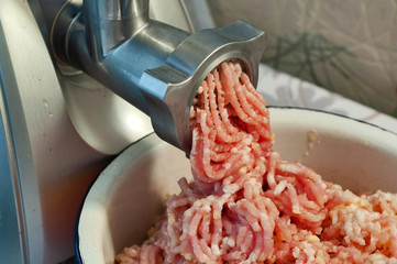 Cooking - minced meat for homemade meatballs is grinded in an electric meat grinder