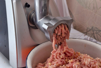 Cooking - minced meat for homemade meatballs is grinded in an electric meat grinder