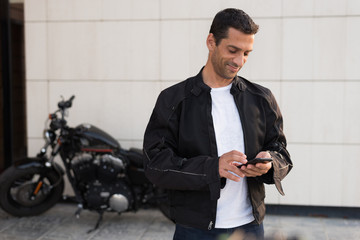Black dressed biker man looking his smartphone.
