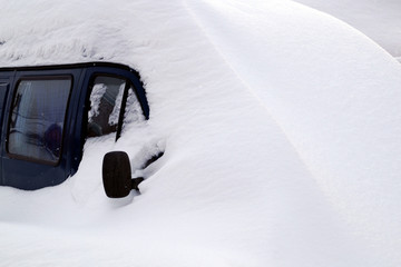 The car is covered in snow after heavy snowfall.