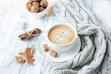 Cup of coffee, brown sugar, knitted scarf, garland. Autumn mood. Cozy autumn composition. Hygge concept. Soft focus