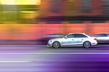 the car drives  fast along a city street, overtakes other vehicles, blurred focus