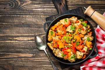 Chicken Stir fry with vegetables on wooden table.