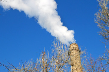 plant tubes with white smoke on blue sky, chemical plant towers of nuclear power plant against the...