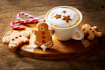 Christmas drink. Cup of cappuccino coffee with stars drawing and gingerbread cookie