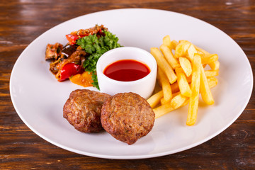 Meat cutlets with French fries, vegetables and tomato sauce