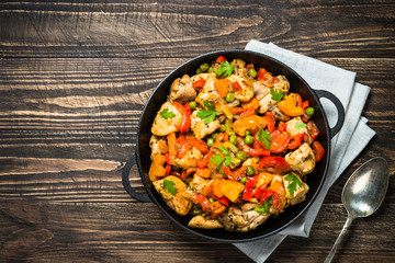 Chicken Stir fry with vegetables on wooden table.