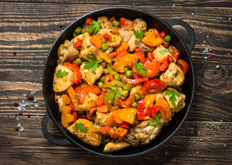 Chicken Stir fry with vegetables on wooden table.
