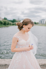 Beautiful young bride in white wedding dress holding flower at nature