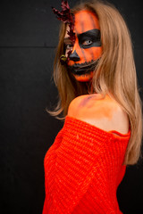 Young blonde girl with halloween face art posing outdoor.  Helloween celebration concept.