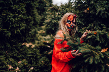 Young blonde girl with halloween face art posing outdoor.  Helloween celebration concept.