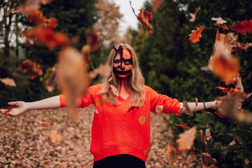 Young blonde girl with halloween face art posing outdoor.  Helloween celebration concept.
