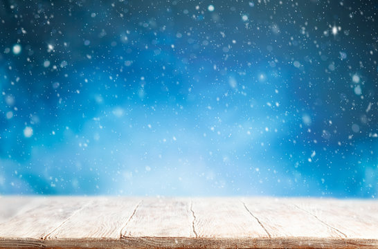 Beautiful winter background with wooden old desk and blurred blue sky. Winter, New Year and Christmas concept with snowy background.