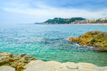 Sand beach with rocks in cloudy weather in Lloret de Mar, Costa Brava Spain. Concept of rest.