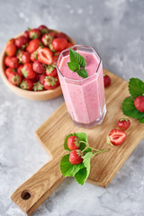 Strawberry milk shake in a glass jar and fresh strawberries with leaves