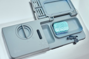 putting soap tablet in the dishwasher machine, close up. Kitchen domestic appliance concept