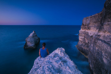 A man sitting on a rock in front of the sea