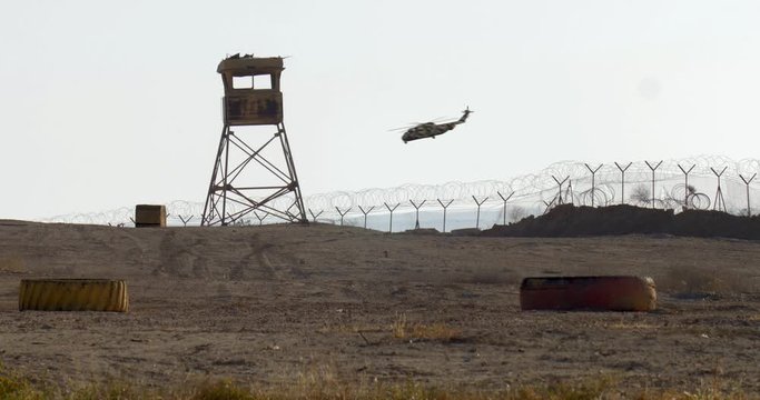 Military Watch Tower with  Helicopter Flying Over  Military Helicopter Flying Over Abandoned Watch Tower Base