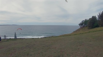 Paragliders Paragliding. People Watching Para Gliders Gliding High In Windy Cloudy Sky At Pat Morton Lookout Headland Sea Coastline Hills.Outdoor Leisure Activity.Lennox Head Landscape Australia