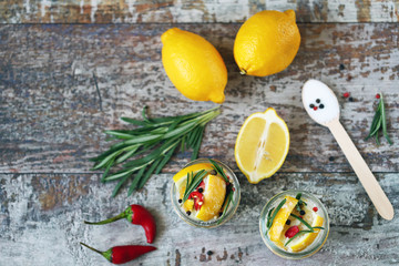 Fermented lemons in jars of salt, chili pepper and rosemary. Probiotics Fermented food. Pickled lemons.