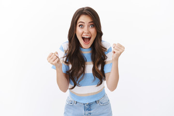 Cheerful lucky pretty tender woman, fist pump raising hands cheering, rooting for team, winning huge bet, playing casino thrilled, encourage friend score, watching football game, white background © Cookie Studio
