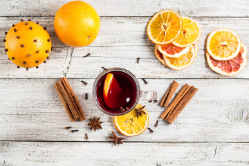 Glass of delicious mulled wine with oranges anise cinnamon on white wooden table