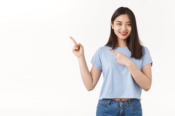 Outgoing glad pleasant friendly brunette asian girl pointing upper left corner smiling amused keep...