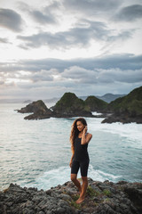 Young sportswoman of the top of hill with mountains view. Hiking on ocean coast