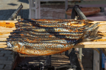 Fresh grilled mackerel fish on the wooden stick. Fish kebab. Naplavka street food market.