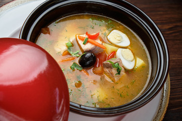 Fish soup in a pot with a red lid. catering menu