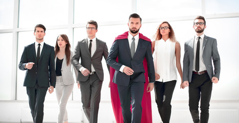 businessman in a red superhero cloak and his business team © ASDF