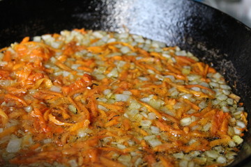  photo fried onions and carrots in vegetable oil.cooking in a cast iron skillet at home kitchen.