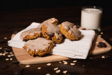 gourmet oatmeal chocolate chip cookies with a glass of milk on a cutting board and cloth