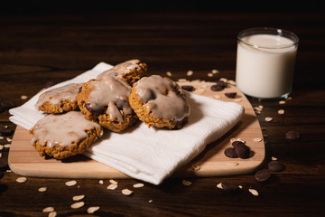 gourmet oatmeal chocolate chip cookies with a glass of milk on a cutting board and cloth